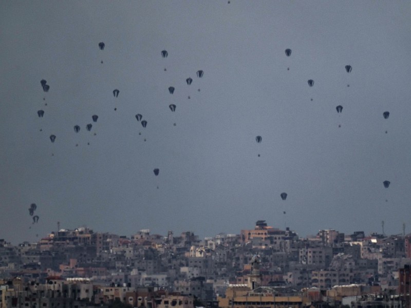 Parachutes drop aid into the northern Gaza Strip, as seen from southern Israel, Friday, March 8, 2024. (AP Photo/Leo Correa)