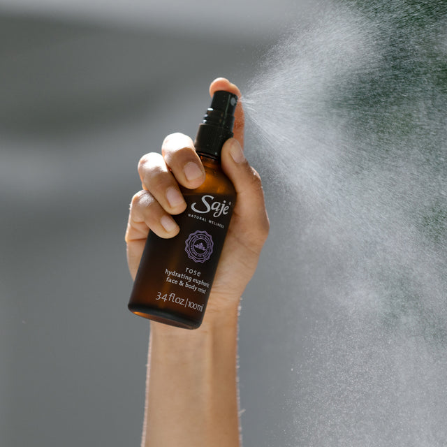 A hand spraying rose face and body mist