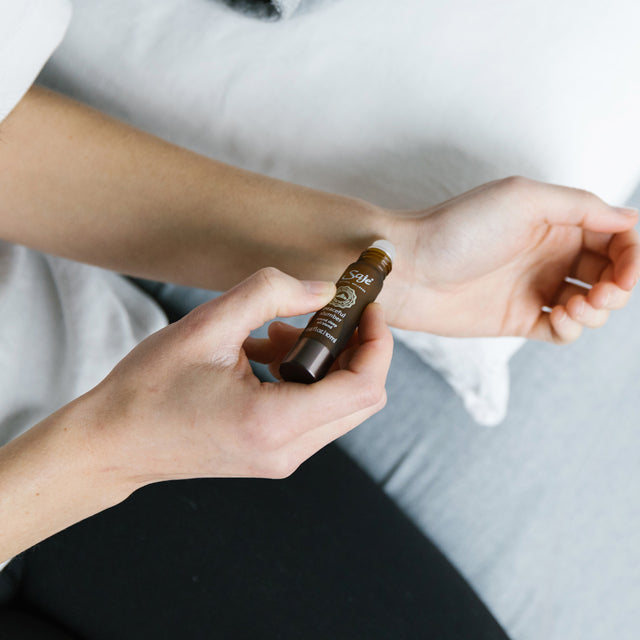 A person applying Peaceful slumber remedy roll-on onto their pulse point 